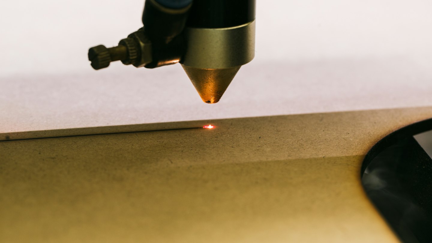 Faisceau de graveur laser gravant un motif dans du bois.