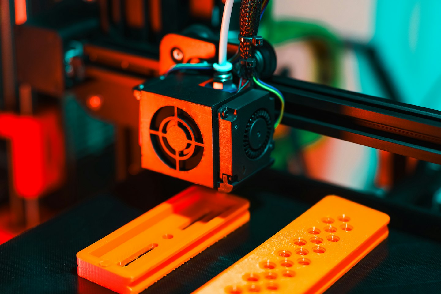 Imprimante 3D extrudant du filament orange sur un plateau d'impression.