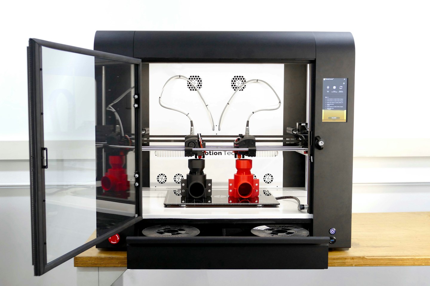 Imprimante 3D industrielle noire, porte entrouverte dans un atelier.